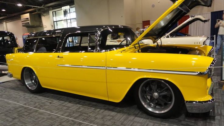 an old yellow car parked in a showroom