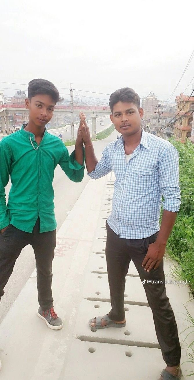 two young men standing next to each other in front of a bridge holding their hands