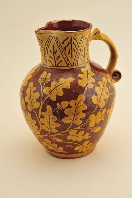 a brown and yellow vase sitting on top of a table