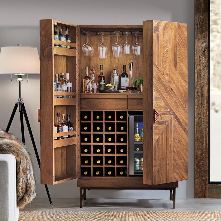 an armoire with wine glasses and bottles in it is next to a couch that has a rug on the floor