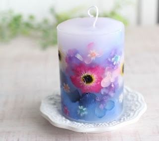 a candle that is sitting on a plate with flowers painted on it and the candles are lit