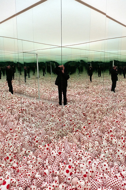 two people standing in front of a mirror with red and white balls all over it