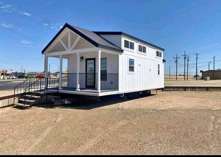 a tiny white house sitting on top of a dirt field