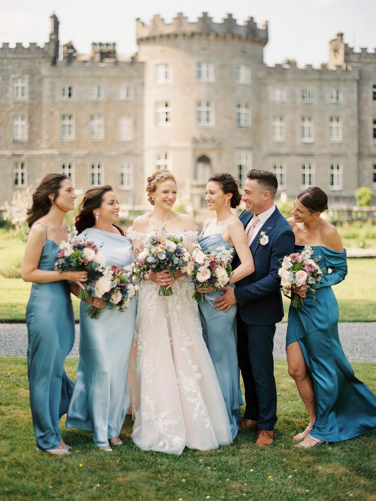 a group of people standing in front of a building with flowers on their heads and dresses