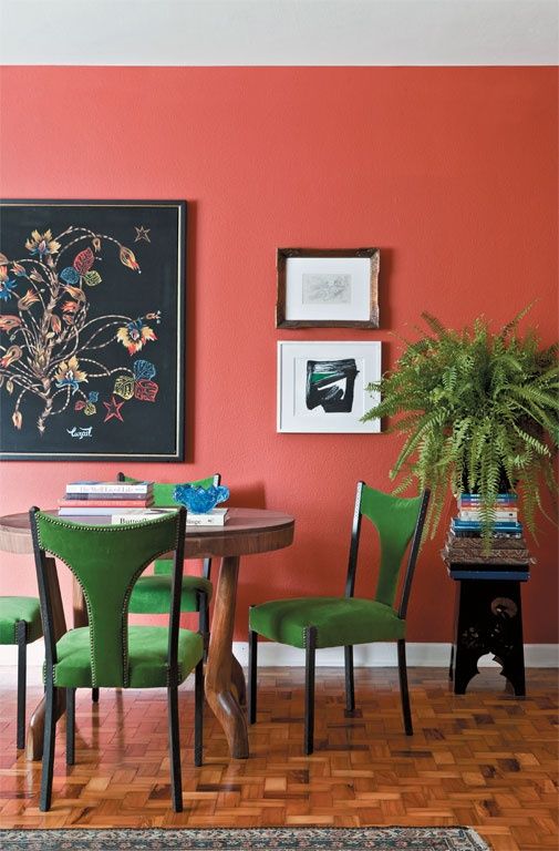 a dining room with pink walls and green chairs