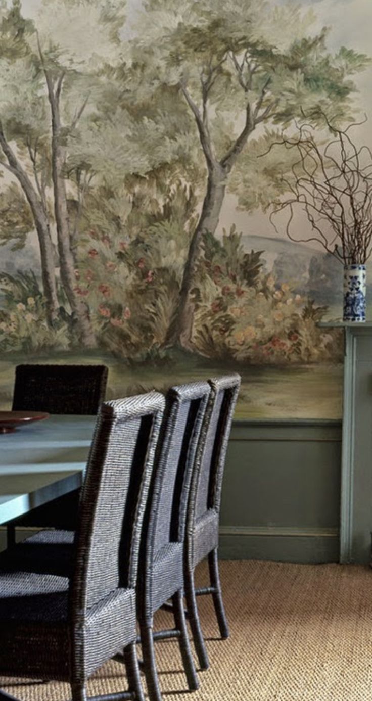 a dining room table with four chairs and a painting on the wall behind it in front of a fireplace