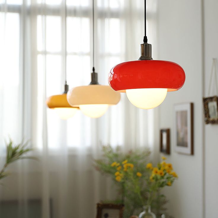 three lights hanging from a ceiling in a room with flowers and pictures on the wall