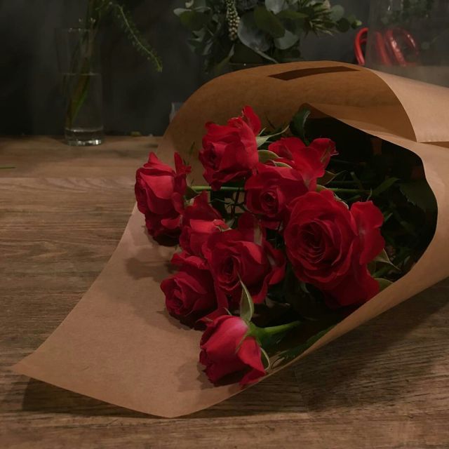 a bouquet of red roses is wrapped in brown paper