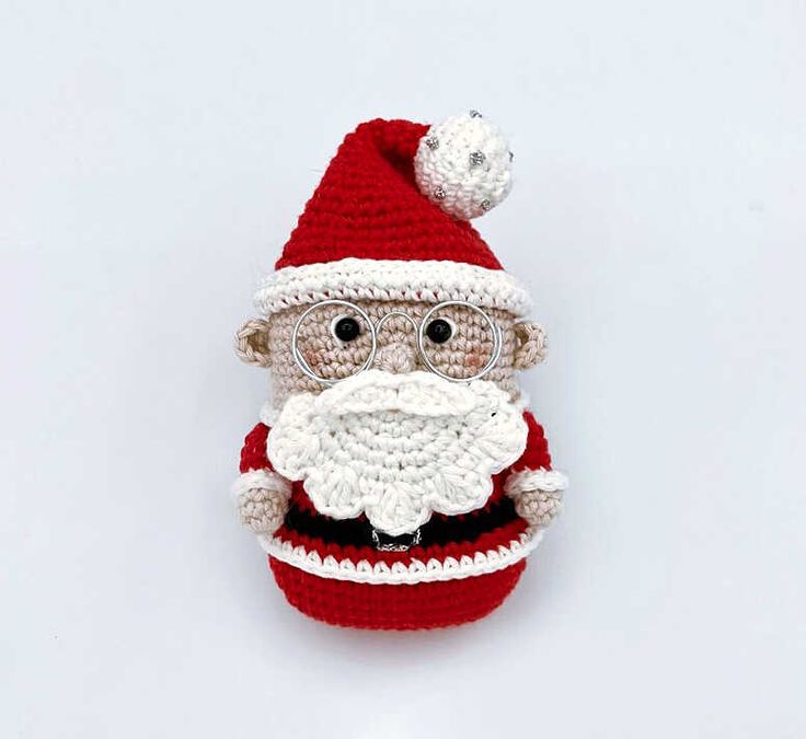 a crocheted santa clause hat with glasses and a beard on the top, sitting in front of a white background