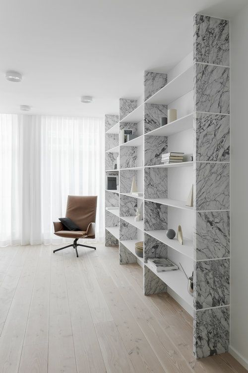 an empty room with a chair, bookshelf and marbled bookcases