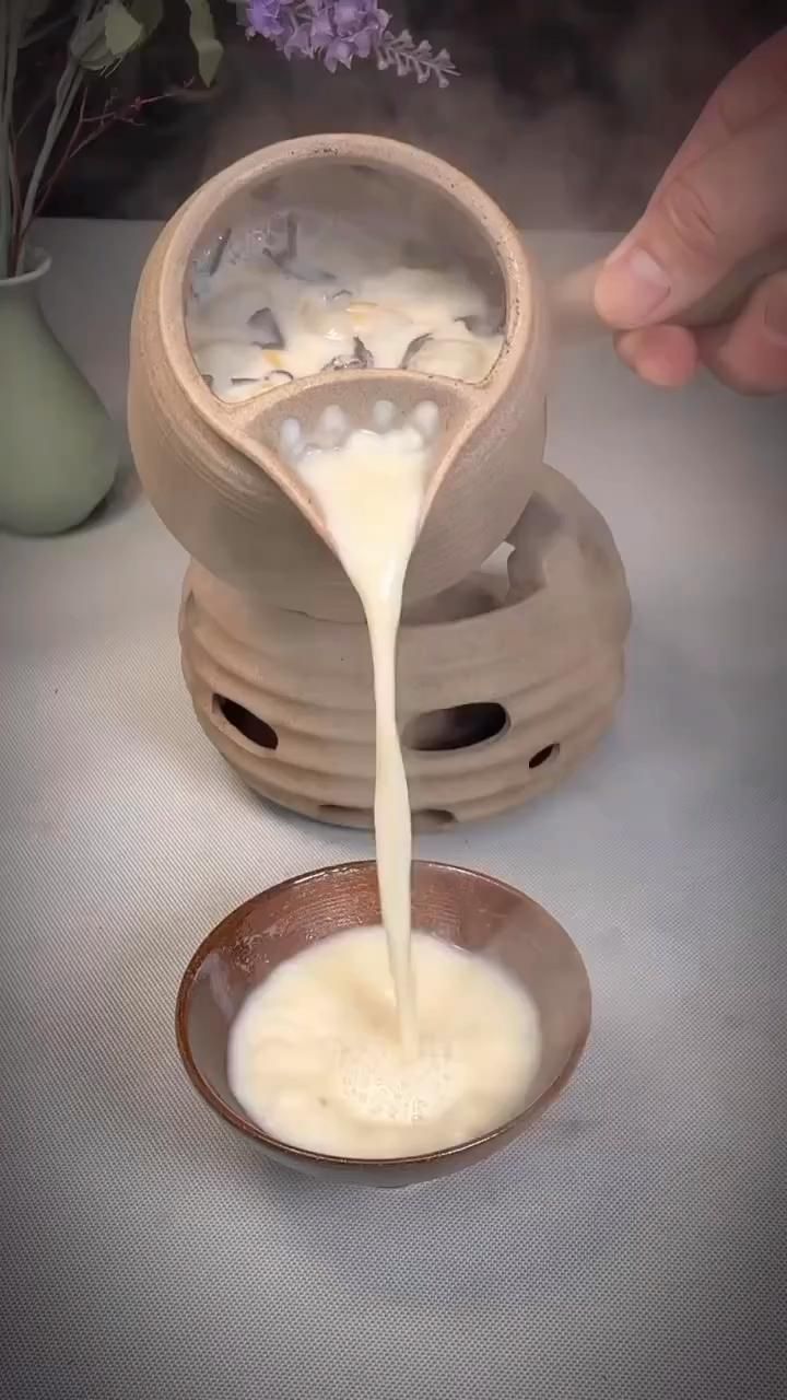 a person pouring milk into a bowl on top of a table