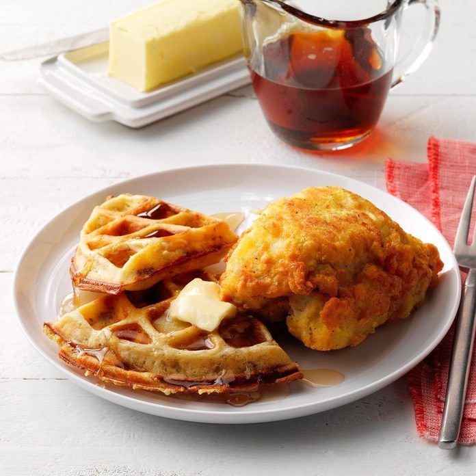 a white plate topped with waffles next to a cup of tea and butter