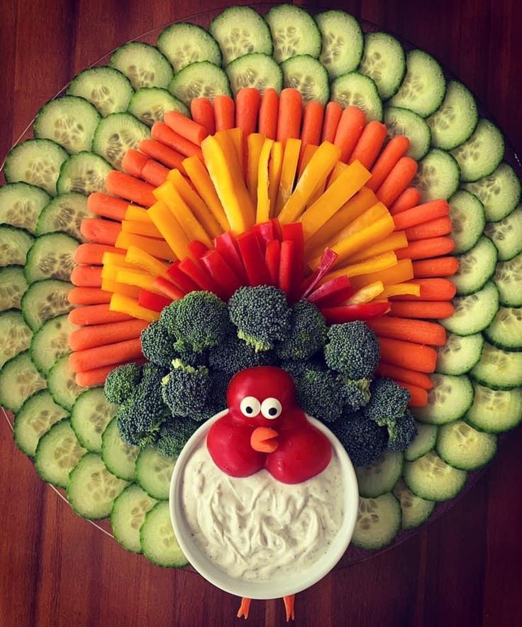 a turkey made out of vegetables and carrots on top of a platter with dip in the middle