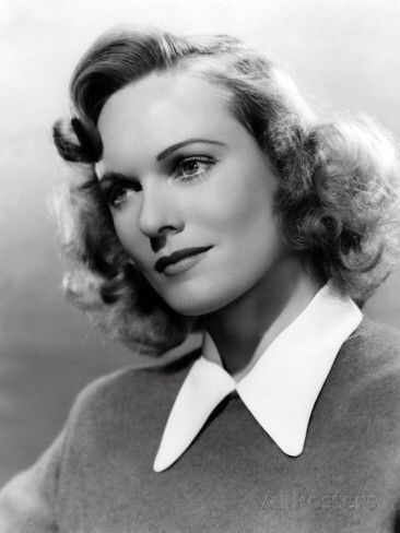 an old black and white photo of a woman with short hair wearing a collared sweater