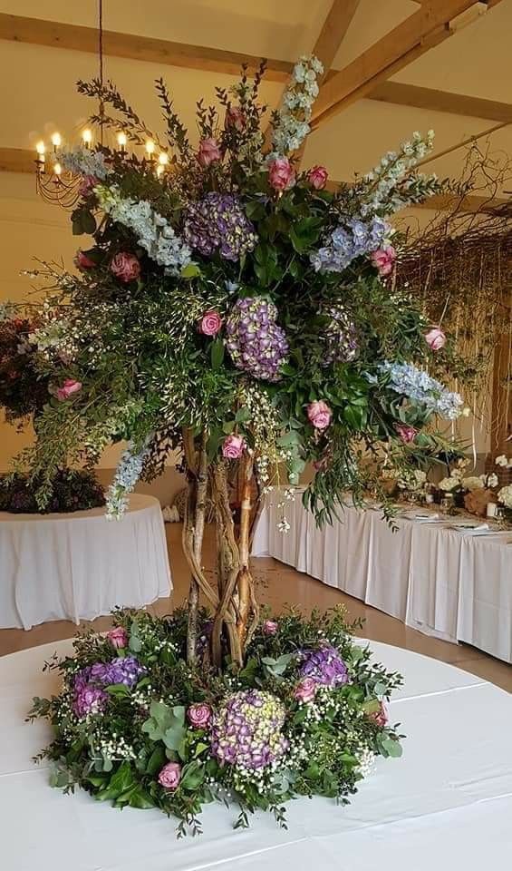 an arrangement of flowers on a table in a room with tables and white linens