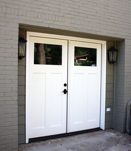 two white double doors in front of a brick building