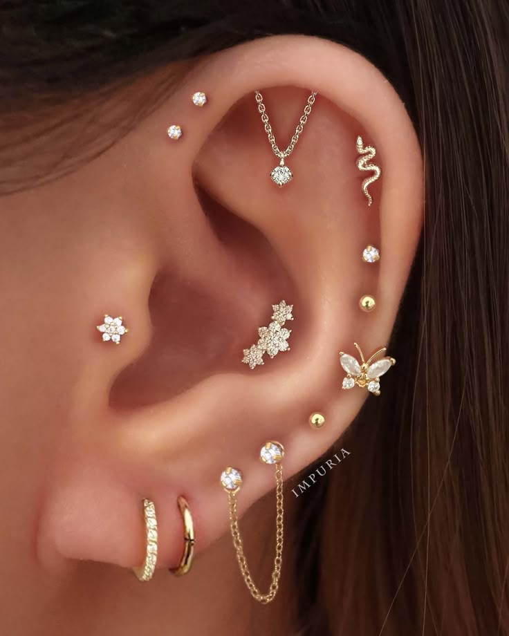 a woman wearing three different piercings on her ear and one has two butterflies in the middle