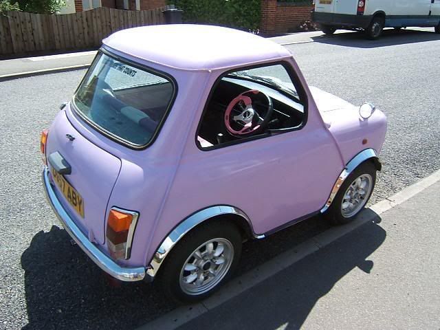 a small pink car is parked on the street