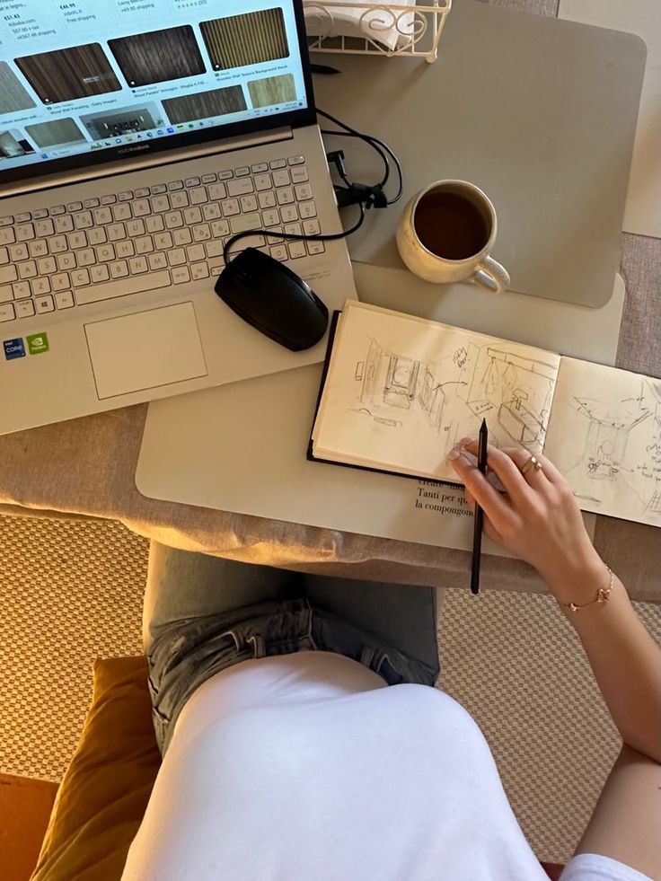 a person sitting at a desk with a laptop and notebook