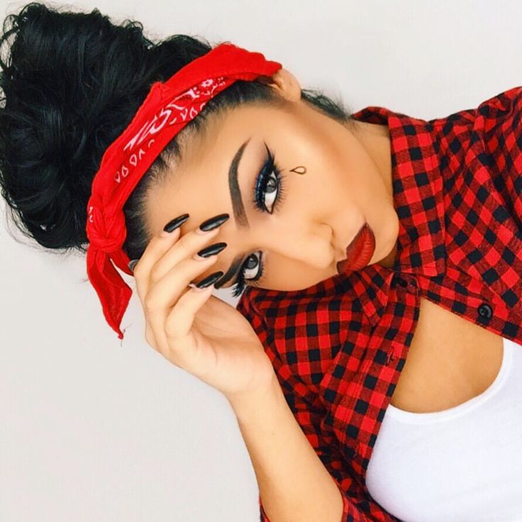 a woman with black and red makeup is holding her hand to her face while looking at the camera