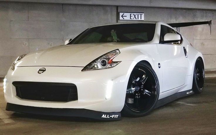 a white nissan sports car parked in a parking garage with an exit sign above it