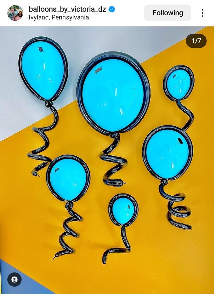 some blue balloons are hanging on a yellow and white wall with the words balloon by victoria