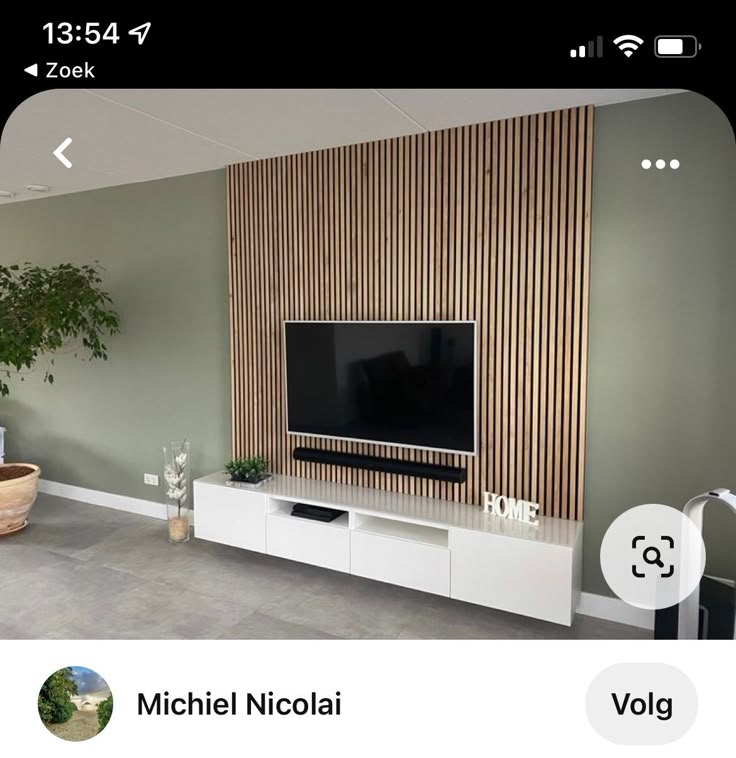 a flat screen tv sitting on top of a white entertainment center next to a potted plant