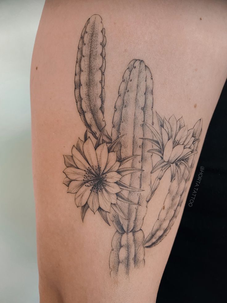 a woman's arm with a cactus and flower tattoo on the left side of her body