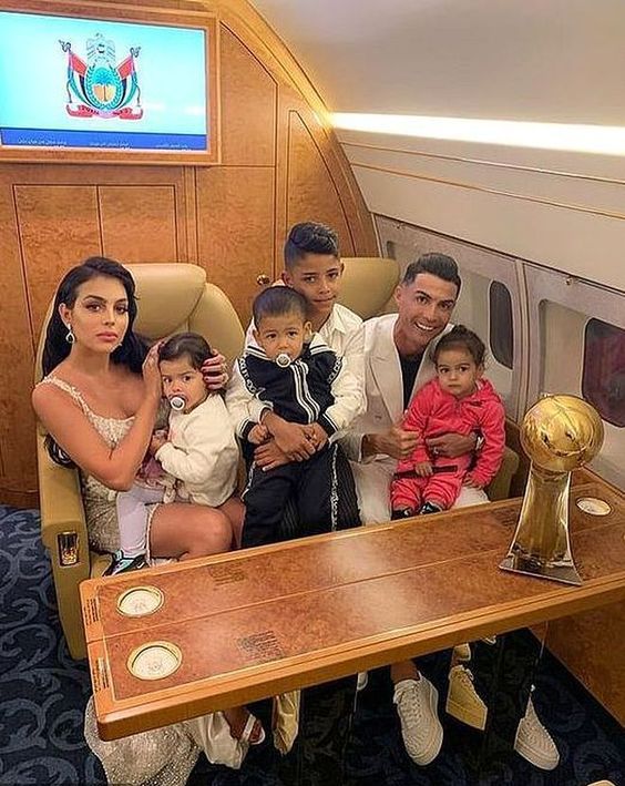 a group of people sitting on top of an airplane next to a table with a trophy