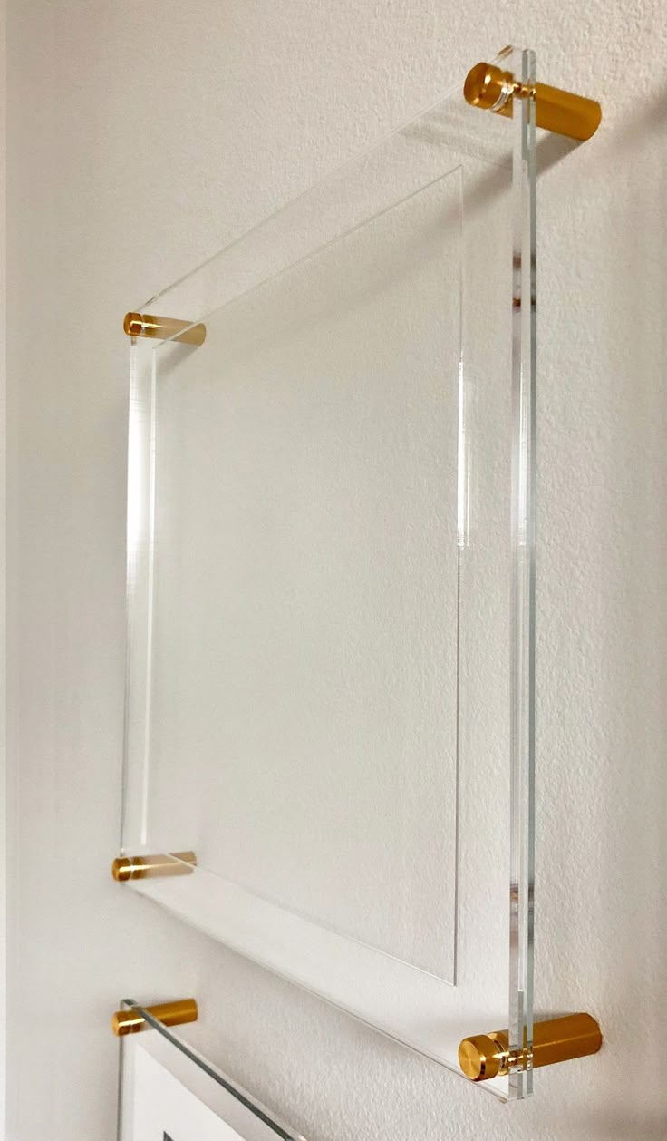 two glass shelves with gold handles on the wall