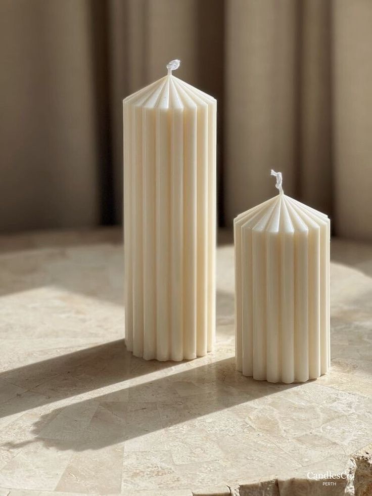 two white candles sitting next to each other on a table