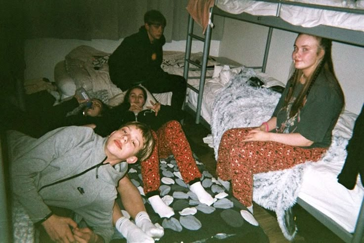 several people sitting on bunk beds in a dorm room with one person smiling at the camera