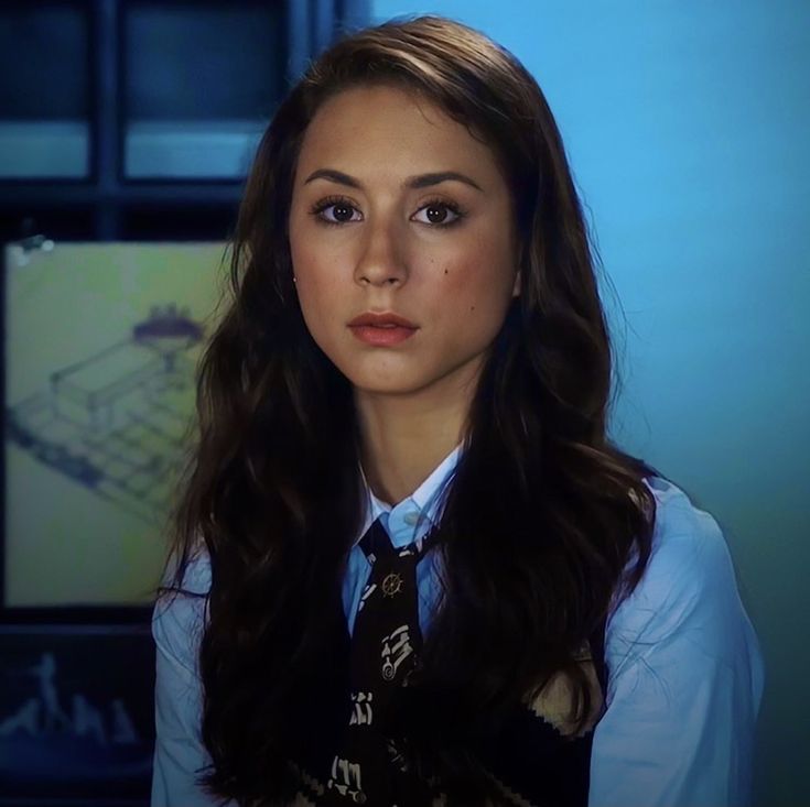 a young woman wearing a neck tie in front of a tv screen with the caption's name on it