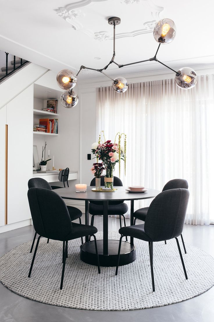 a dining room table with four chairs and a chandelier hanging from the ceiling