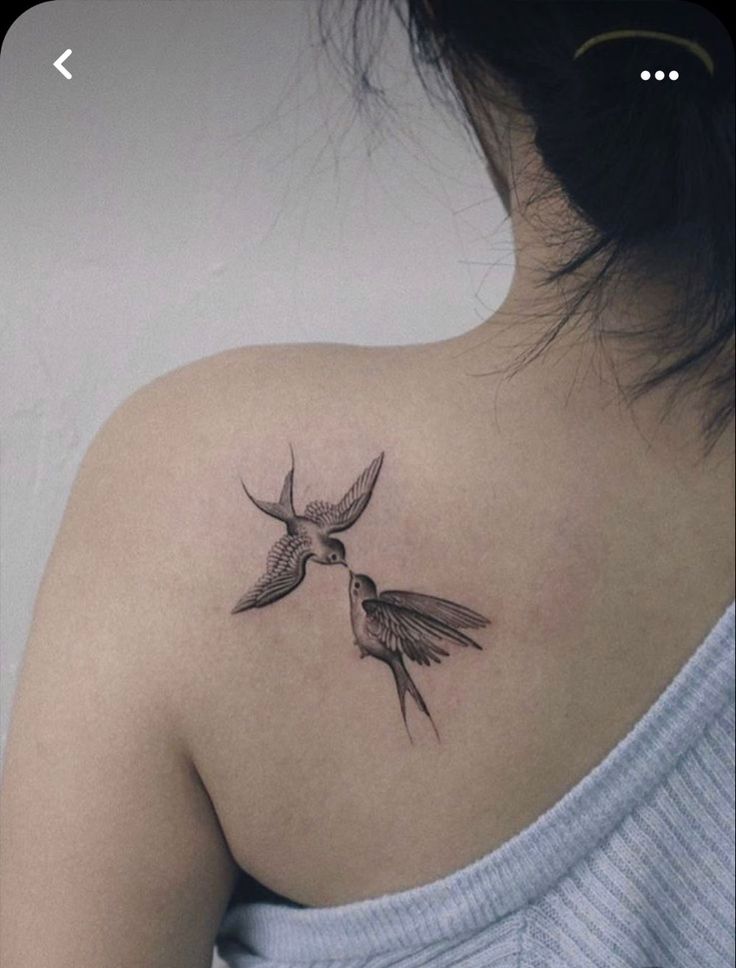 the back of a woman's shoulder with two birds on it