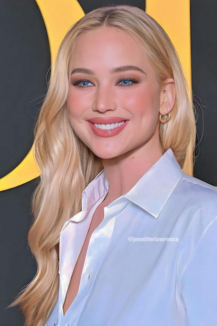 a woman with blonde hair and blue eyes wearing a white shirt smiling at the camera