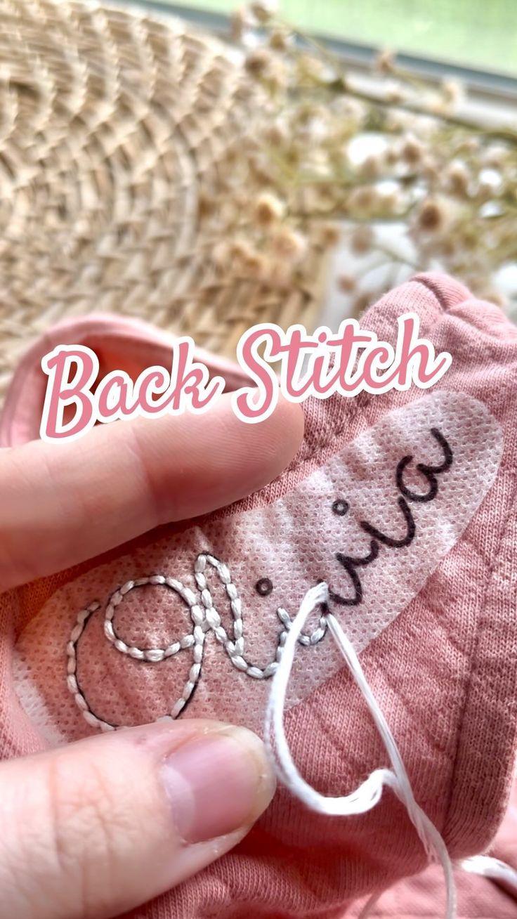 someone is holding their pink socks with the word back stitch on it