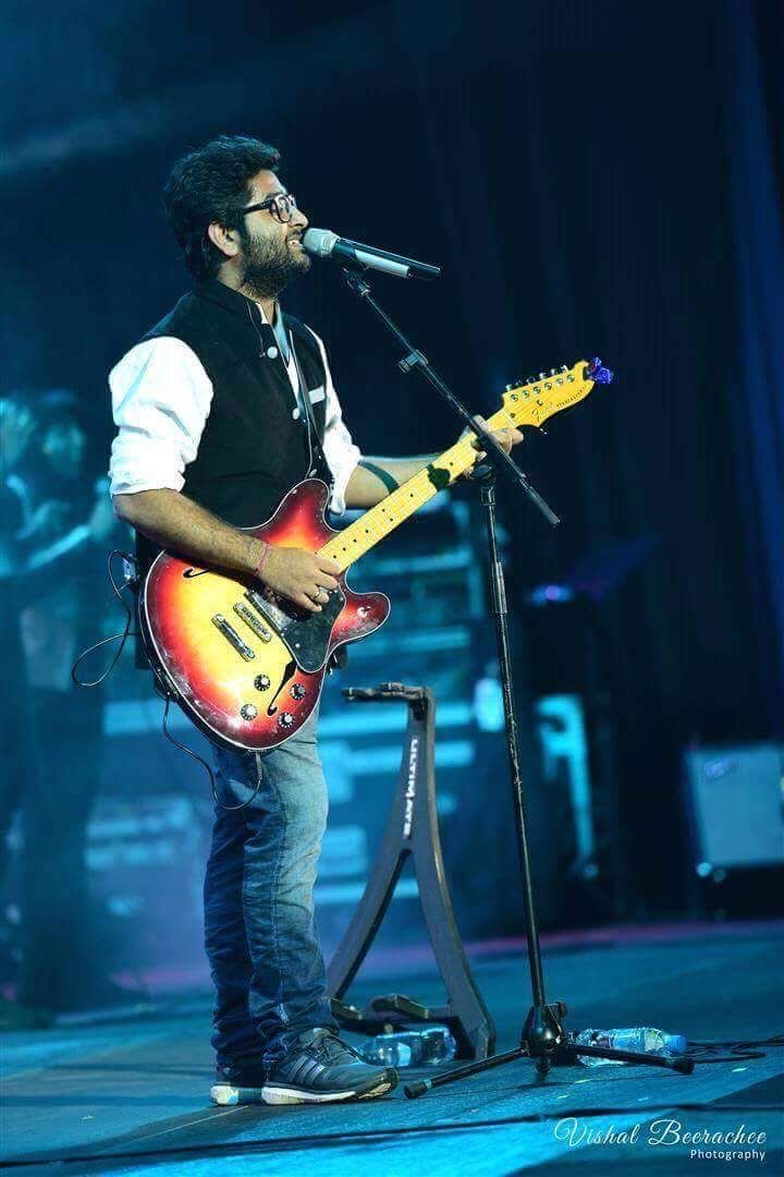 a man standing on top of a stage holding a guitar