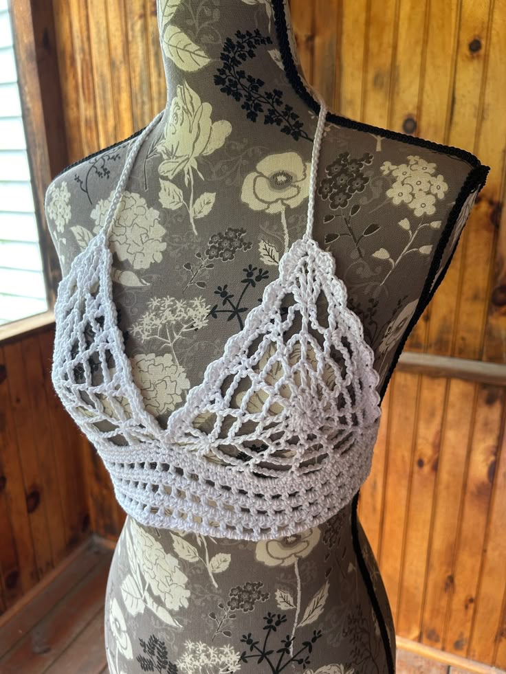 a mannequin wearing a white crochet top with floral designs on it