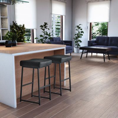 an office with two bar stools next to a counter and couches in the background