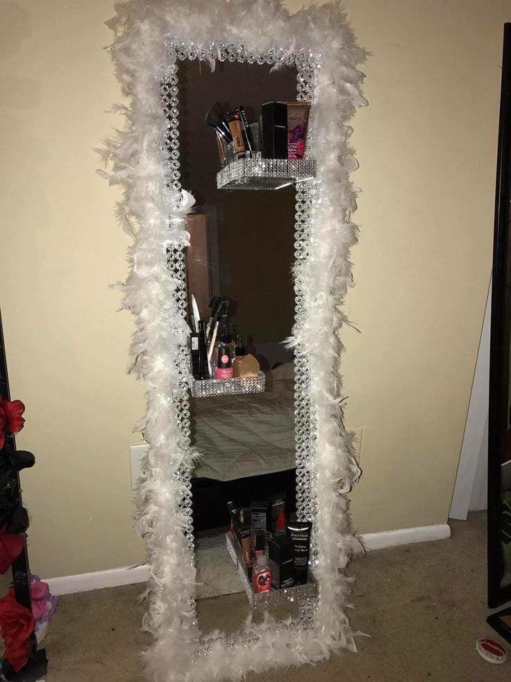 a tall white mirror sitting on top of a floor next to a shelf filled with cosmetics