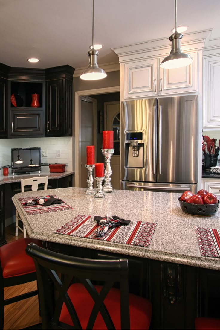 a kitchen with black cabinets and white countertops has red accents on the table runner