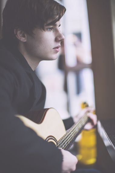 a young man is playing an acoustic guitar