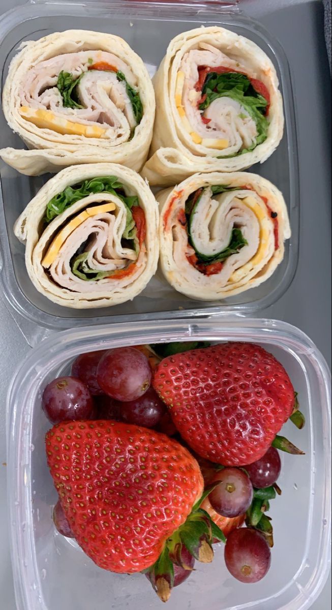 two plastic containers filled with sandwiches and strawberries