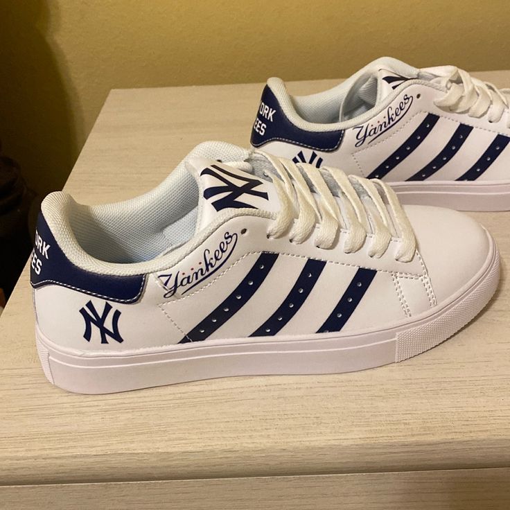 a pair of new york yankees white and blue shoes on top of a wooden table