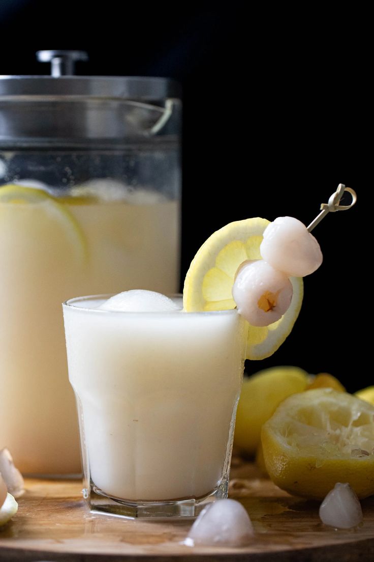 a glass filled with liquid next to sliced lemons