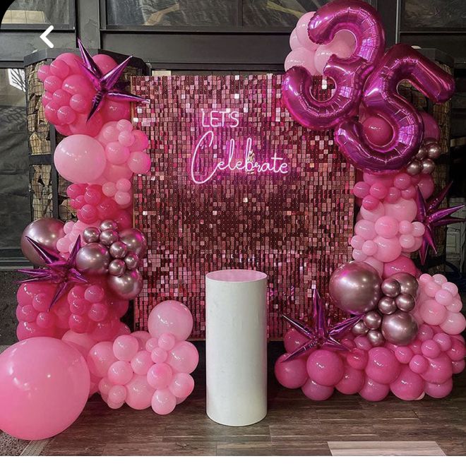 balloons and streamers are set up in front of a pink 30th birthday party backdrop