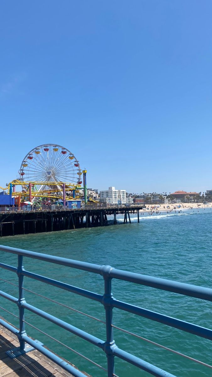 an amusement park next to the ocean with a ferris wheel