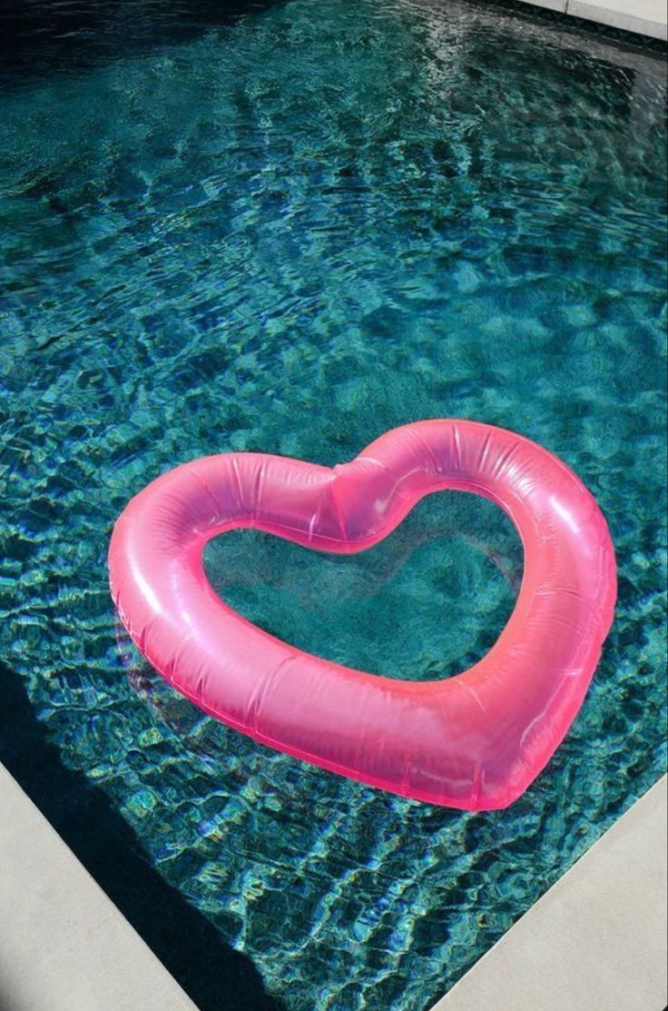 an inflatable heart shaped float floating on top of a swimming pool