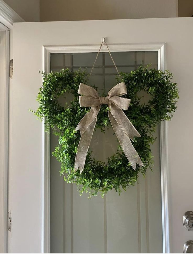 a wreath hanging on the front door is adorned with a bow and greenery for an elegant touch